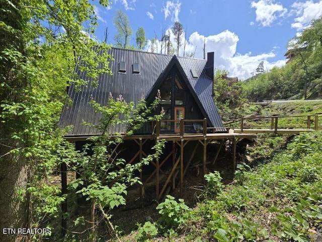 rear view of property with a chimney, a wooden deck, and metal roof
