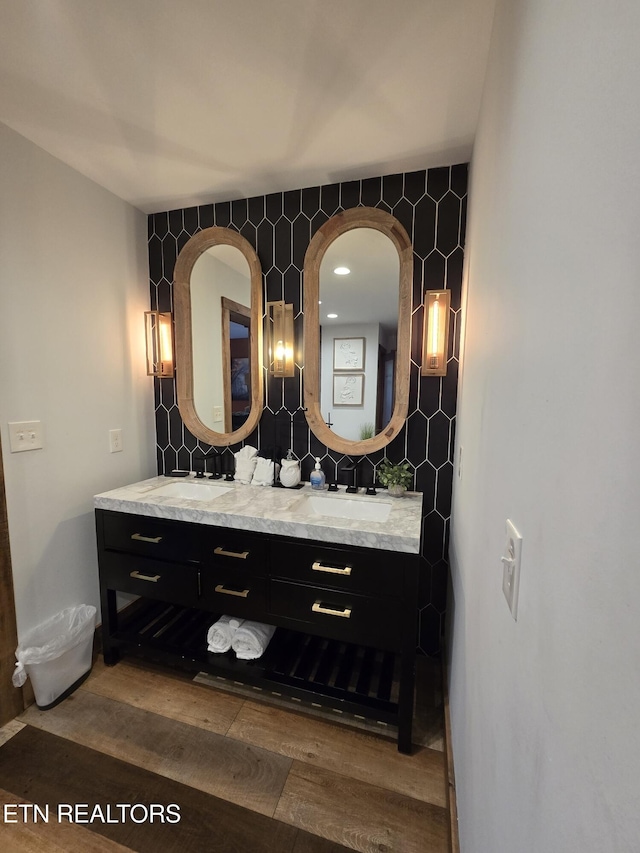 bathroom with tasteful backsplash, wood finished floors, double vanity, and a sink