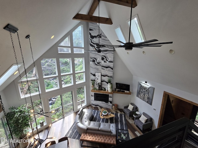 living room featuring wood finished floors, a ceiling fan, high vaulted ceiling, and beamed ceiling