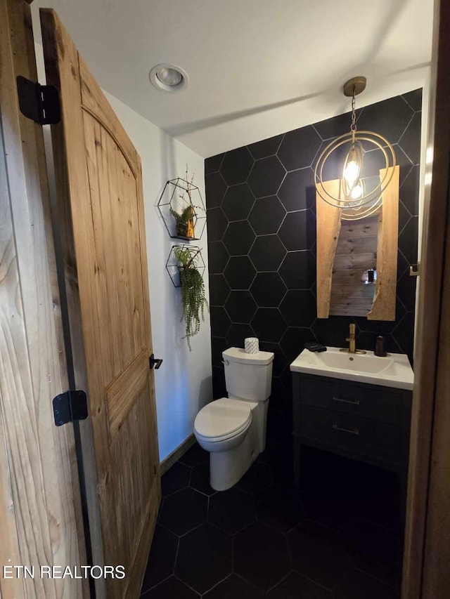 bathroom featuring toilet, tile walls, and vanity
