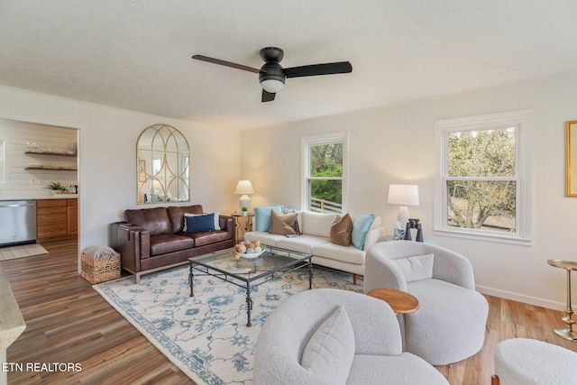 living area with a textured ceiling, wood finished floors, a ceiling fan, and baseboards