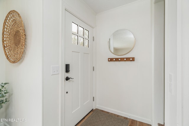 doorway featuring baseboards, wood finished floors, and ornamental molding