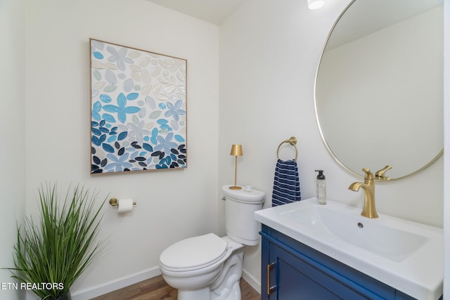 bathroom with wood finished floors, vanity, toilet, and baseboards