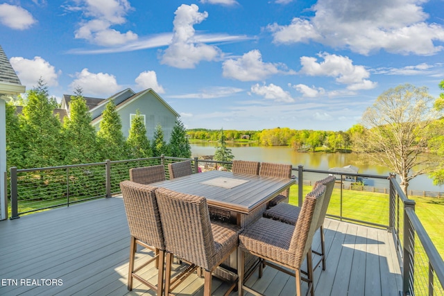 wooden deck with outdoor dining space, a yard, and a water view