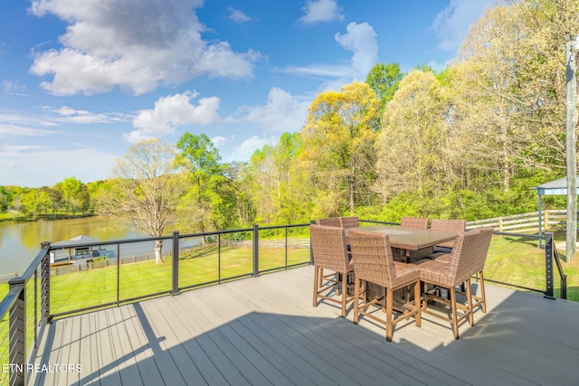 wooden deck with outdoor dining space, a yard, and a water view