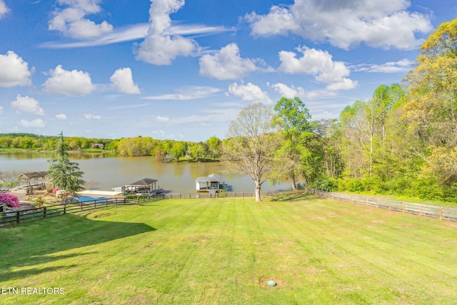 view of yard with fence, a water view, and a floating dock