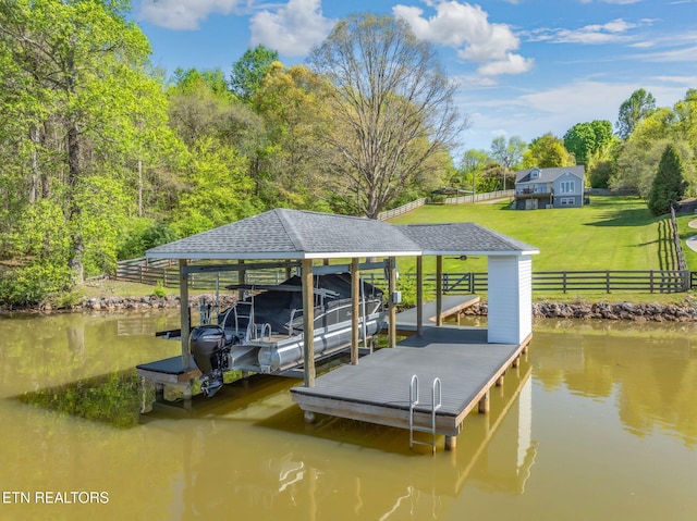 dock area featuring boat lift, fence, a water view, and a lawn