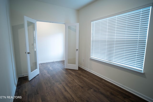 unfurnished bedroom with french doors, dark wood-style flooring, and baseboards