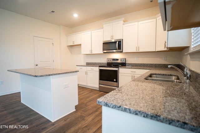kitchen with a sink, stainless steel appliances, dark wood finished floors, and white cabinetry