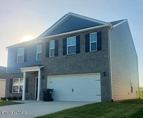 view of front of property featuring an attached garage, driveway, a front lawn, and brick siding