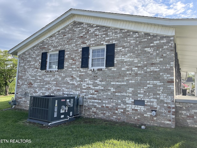view of side of property with central air condition unit and a lawn
