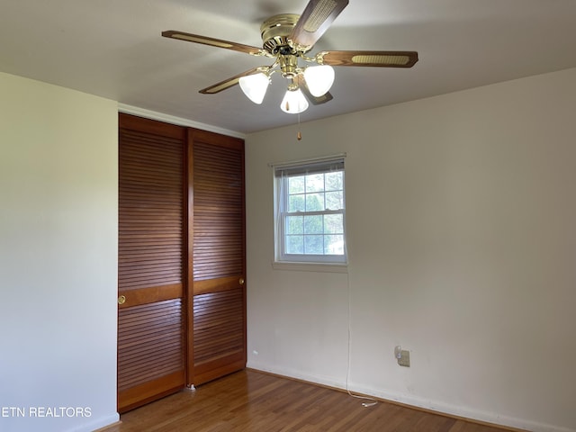 unfurnished bedroom with a closet, wood finished floors, baseboards, and ceiling fan