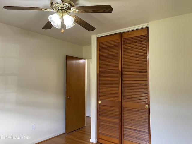 unfurnished bedroom featuring baseboards, a closet, ceiling fan, and wood finished floors