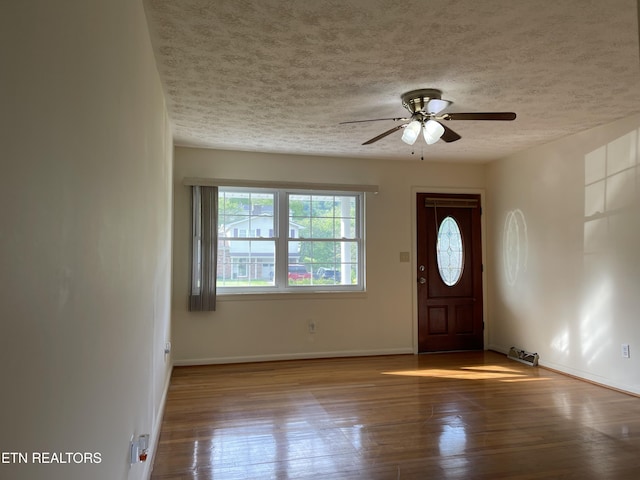 foyer featuring a textured ceiling, wood finished floors, baseboards, and ceiling fan