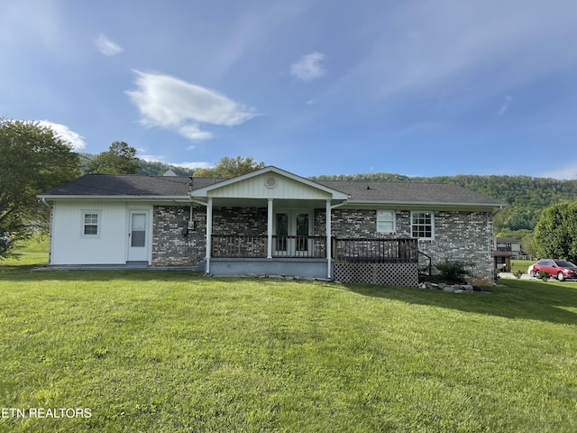 back of house featuring a lawn and a wooden deck