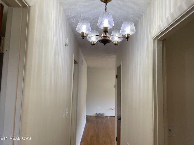 corridor featuring a chandelier and wood finished floors