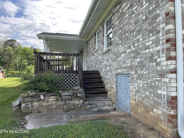 view of property exterior with a lawn, a wooden deck, and stairs