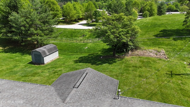 view of community with an outdoor structure, fence, a lawn, and a storage unit