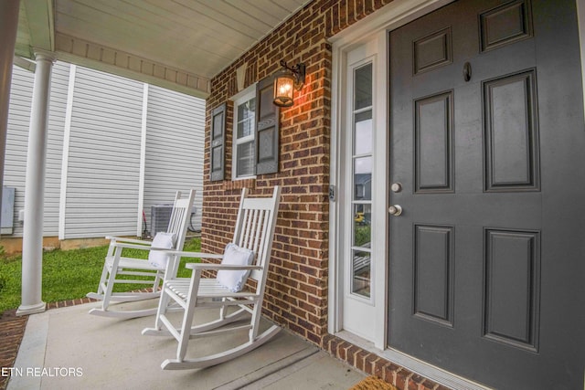 property entrance featuring covered porch and brick siding