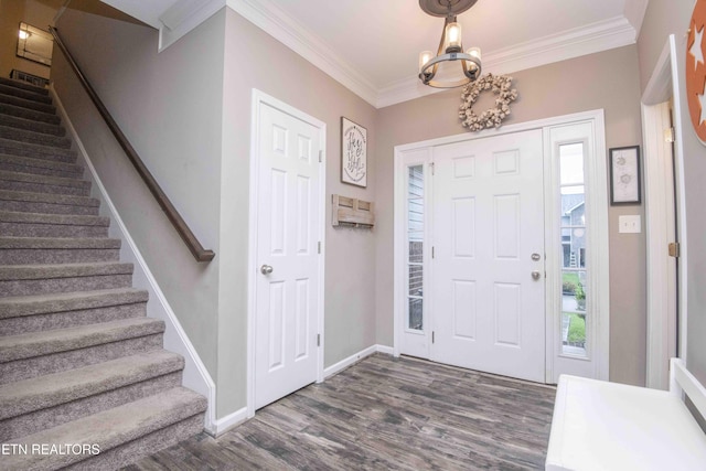 entrance foyer featuring dark wood finished floors, stairs, ornamental molding, healthy amount of natural light, and a chandelier