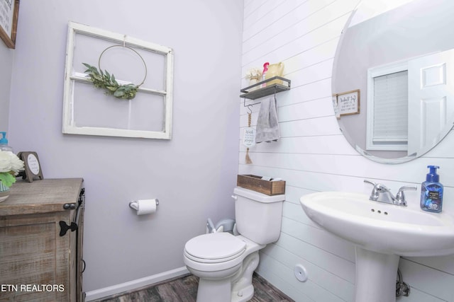 bathroom with wood finished floors, toilet, baseboards, and wood walls