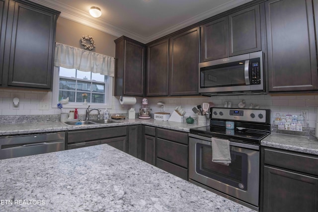 kitchen with stainless steel appliances, a sink, crown molding, tasteful backsplash, and dark brown cabinetry