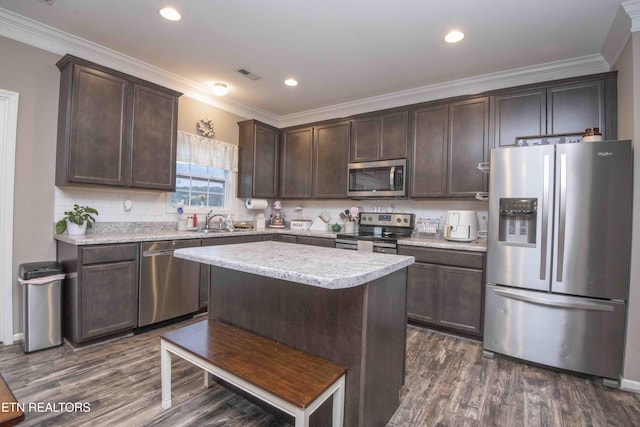 kitchen featuring appliances with stainless steel finishes, dark brown cabinetry, dark wood-style flooring, tasteful backsplash, and crown molding