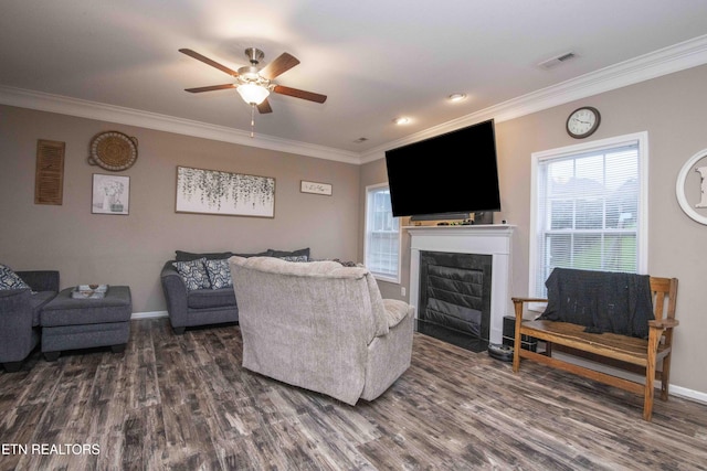 living room featuring dark wood-type flooring, ceiling fan, ornamental molding, a fireplace with flush hearth, and baseboards