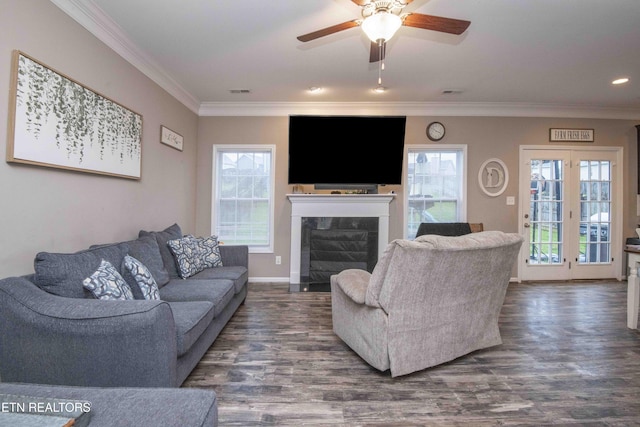 living room featuring ornamental molding, ceiling fan, a fireplace with flush hearth, dark wood finished floors, and healthy amount of natural light