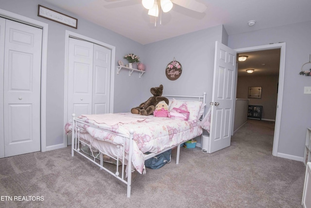 carpeted bedroom with baseboards, ceiling fan, and multiple closets