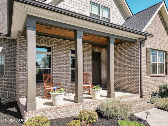 doorway to property featuring a porch and brick siding