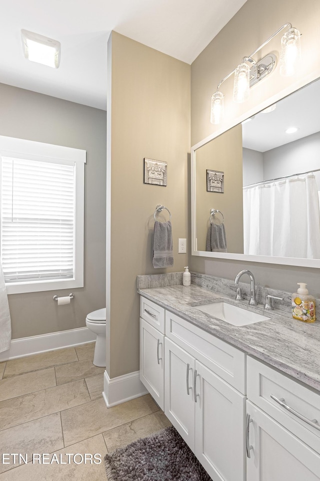bathroom with baseboards, toilet, tile patterned flooring, and vanity