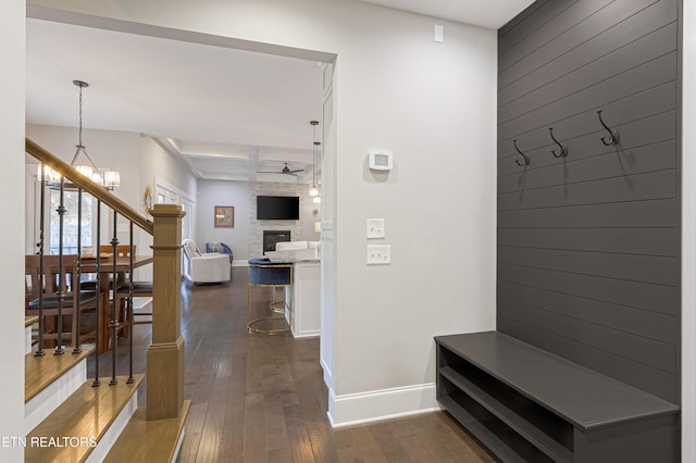 mudroom featuring a large fireplace, coffered ceiling, baseboards, an inviting chandelier, and dark wood-style flooring