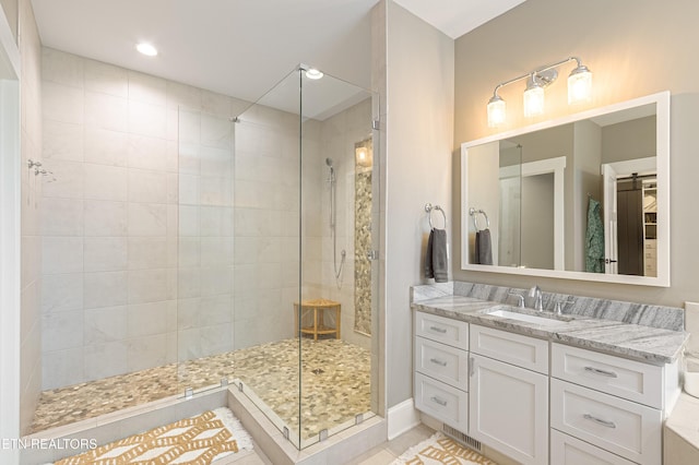 full bathroom featuring tiled shower and vanity