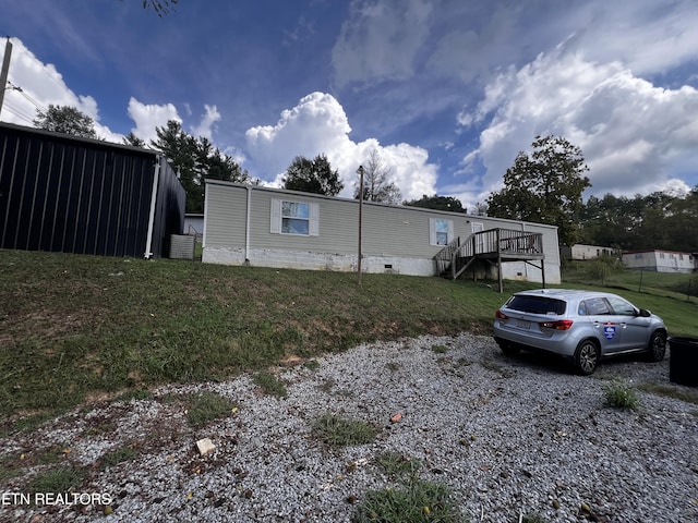view of side of home featuring crawl space, a deck, a yard, and stairway