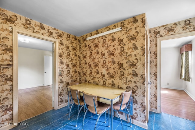 unfurnished dining area featuring baseboards, tile patterned floors, and wallpapered walls