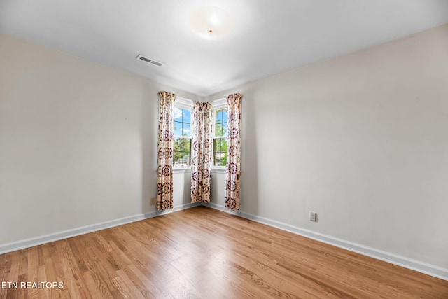 unfurnished room with baseboards, wood finished floors, and visible vents