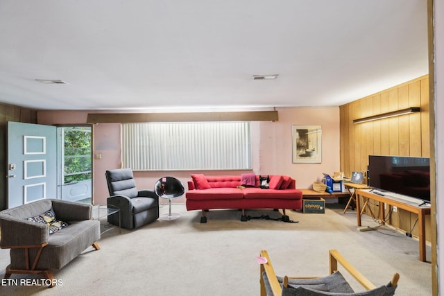 carpeted living room featuring visible vents and wooden walls
