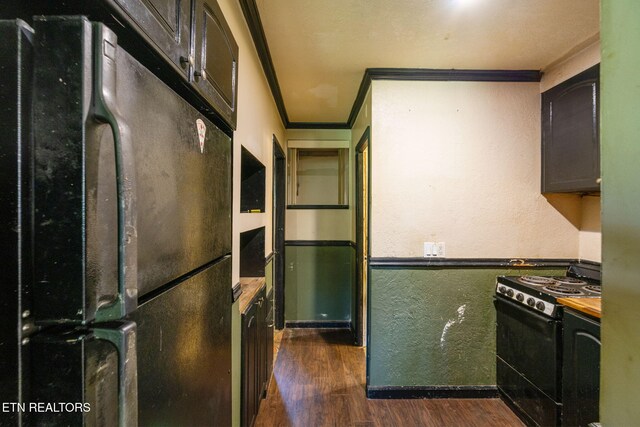 kitchen with dark wood-style flooring, crown molding, baseboards, black appliances, and a textured wall