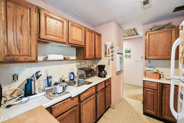 kitchen featuring backsplash, visible vents, white oven, light countertops, and light floors