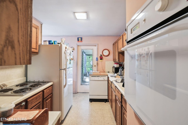 kitchen with brown cabinetry, light countertops, light floors, and white appliances