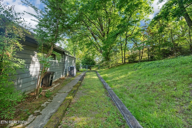 view of yard with central AC and fence