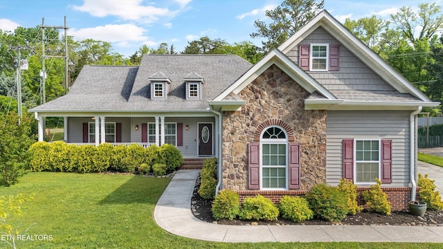 view of front of home with roof with shingles, a porch, a front lawn, and stone siding