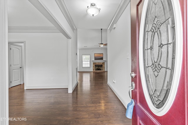 entrance foyer featuring crown molding, wood finished floors, baseboards, a fireplace with raised hearth, and a ceiling fan