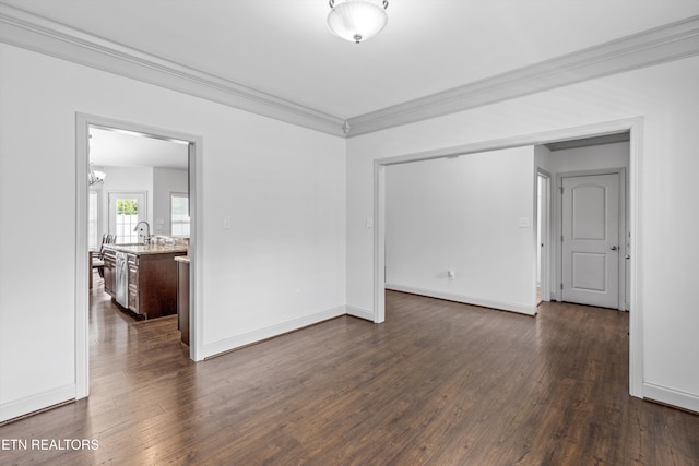 empty room featuring crown molding, dark wood finished floors, baseboards, and a chandelier