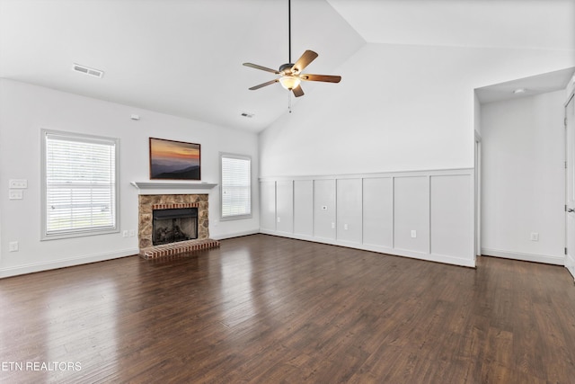 unfurnished living room with a fireplace with raised hearth, ceiling fan, visible vents, and dark wood finished floors