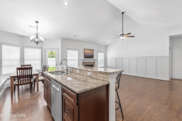 kitchen with stainless steel dishwasher, dark wood-style flooring, dark brown cabinets, a sink, and ceiling fan with notable chandelier