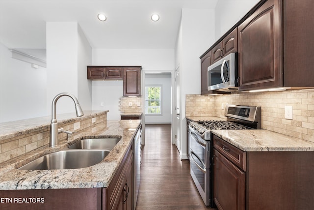 kitchen with a sink, dark brown cabinetry, stainless steel appliances, and dark wood-type flooring