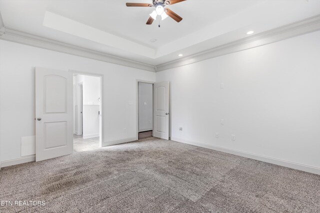 unfurnished bedroom featuring light colored carpet, a raised ceiling, baseboards, ornamental molding, and recessed lighting