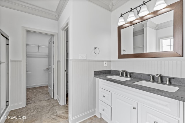 bathroom with double vanity, a walk in closet, ornamental molding, and a sink